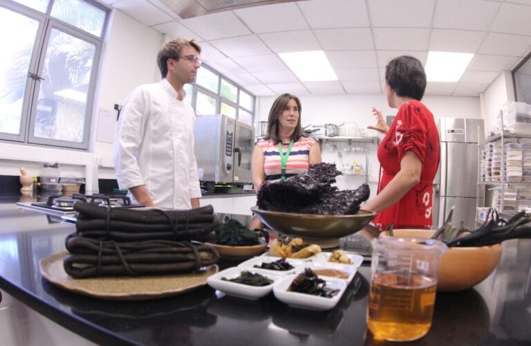 Tres personas conversando en una cocina.