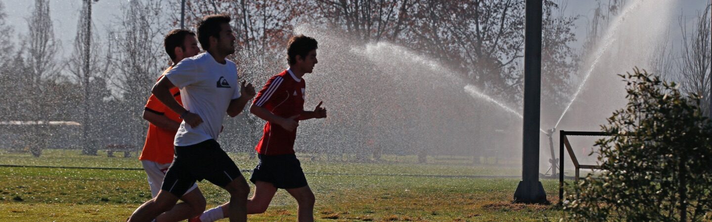 Personas corriendo en una cancha de pasto.
